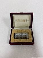 Kinotel 8mm movie lens resting inside an open maroon velvet-lined case, satin lid interior with faint Kinotel branding visible.