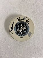 Side of hockey puck with Rejean Houle autograph and NHL official licensed product logo.