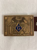 Front view of solid bronze vintage Freemason belt buckle featuring embossed Masonic symbols including the square and compass with blue 'G', all-seeing eye, columns, gavel, and trowel.