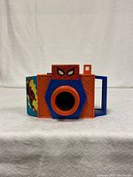Front view of Spiderman-themed film camera showing colorful design with Spiderman face detail, orange and blue plastic body.