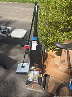 Full view of the Bissell ProHeat carpet shampooer with manual sweeper and parts around