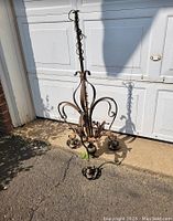 Full view of brass and copper chandelier with curled arm design and decorative candle holders placed upright for display.