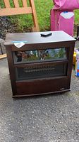 Front view of the Duraflame movable heater with remote control on top, showing wood-like finish and grille