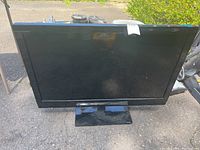 Front image of the Insignia 37-inch TV showing screen and stand outdoors.