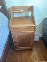 Front view of wood nightstand showing cabinet door closed, drawer, and flat top surface.