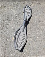 Grey Ripstik caster board placed on pavement, showing top deck and wheels.