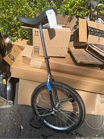 Full view of the unicycle showing the single wheel, metal frame, pedals, and adjustable seat post.