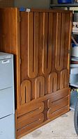 Front view of wood look wardrobe showing two large front doors with unique recessed handles and two lower drawers with matching handles.