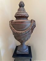 Full view of the large decorative urn showing the overall shape, base, garland details, and finial.