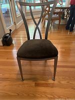 Front view of a contemporary metal desk chair with dark upholstered seat and metal legs on hardwood floor.