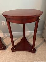 Front and side view of the round wooden end table showing the brass accents on legs and base.