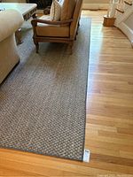 Photo showing long view of large neutral tone contemporary rug with furniture on top, displaying size and condition.