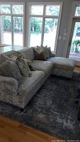 Full view of gray sectional sofa with right-hand chaise positioned in front of windows on area rug