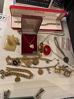 Tray overview of mixed gold jewelry items on white surface