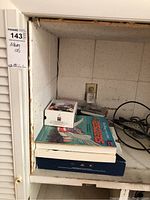 Photo showing several albums, CD sets, and DVDs stacked on a shelf along with some power cords.