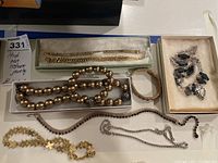 Full view of the costume jewelry lot showing necklaces and bracelets in trays.