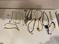 Full view of all 10 costume jewelry necklaces laid out on a flat surface showing the variety of styles and colors.
