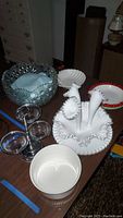 View of the full lot showing the Fenton ruffled tulip vase set with flutes and ruffled edge base plates, crystal bowl with floral and diamond cuts, ceramic seashell bowl, and glass condiment tower.
