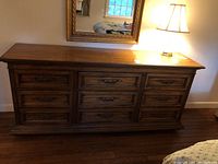 Front view of the wooden dresser showing nine drawers with ornate handles and molded details