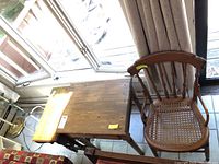 Overhead angled view of wooden gate leg table with leaves extended, showing table surface and part of adjacent furniture.