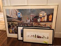 Framed panoramic Newport Rhode Island street scene print with signage and crowds, signed by artist Mark Swensen, behind two smaller framed lighthouse prints.