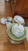 Full view of stacked Royal Bavaria plates with gold and green floral borders, Haviland gravy boat, small Villeroy and Boch bowl, and additional plates and bowls.