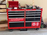 Front view of the red and black two-piece tool chest with drawers, wheels, and lock cylinder visible