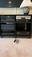 Front view of shelving unit displaying all electronics and two remotes on floor