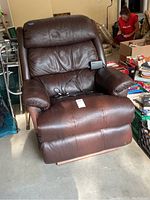 Front view of brown leather electric La-Z-Boy lift chair showing padded armrests and cushioned seat and back with some wear and creases.