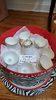 Full view of tea set arranged in a round container with cloth padding, showing teapot, teacups, and creamer