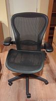 Front view of chair showing black mesh seat and back, armrests and five-star caster base