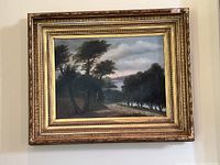 Full view of framed landscape oil painting hanging on beige wall, showing entire frame and artwork.