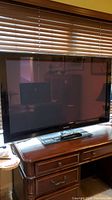 Front view of Samsung 52-inch flat screen television with glossy black frame on wooden desk.