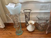 Overview of five vases on wooden floor, showing shapes, sizes, colors, and decorative elements