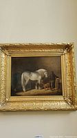 Overall view of framed painting showing horse, handler, dog, and gilded frame
