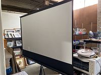 White projection screen with black border set up in a room.