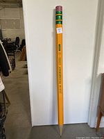 Full view of oversized pencil leaning against wall