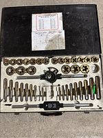 Open tap and die set showing dies, taps and handles in a molded plastic case.