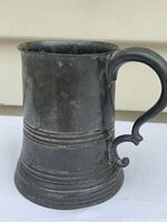 Front view of pewter tankard showing shape, handle, and base details.