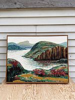 Full front view of framed impressionist oil painting depicting a river or lake with hillside landscape, detailed textured brush strokes and red flowering bushes.