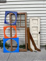 Lot displayed against exterior siding; shows pine multi-pane window, panelled pantry door, three colorful mod plastic panels, and two wooden sock spinning forms.