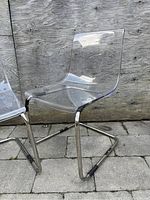 Side view of two clear acrylic chairs showing chrome cantilever frames