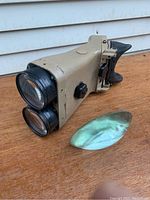 Side view showing beige optic housing, dual stacked objectives and loose curved lens