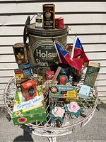 Full view of the lot on a white metal table showing vintage tins, boxes, flags, and floral decor.