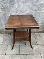 Front view of the antique side table showing the square top, curved legs, and lower shelf, all with original dark varnish finish.