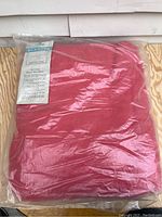 Photo of the red blanket in its original clear plastic packaging showing the sealed condition.