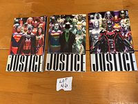 Front cover photos of Justice League Volumes 1, 2, and 3 graphic novels with group character artwork.