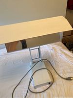 Rectangular light therapy lamp with reflective metal surface and attached power cord.