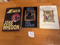 Front view of three graphic novels on table including The Astonishing X-Men, Marvel 1602, Marvel Masterworks Avengers