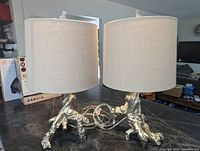 Two silver tree branch style table lamps side by side showing entire lamps including linen shades and cord wires.